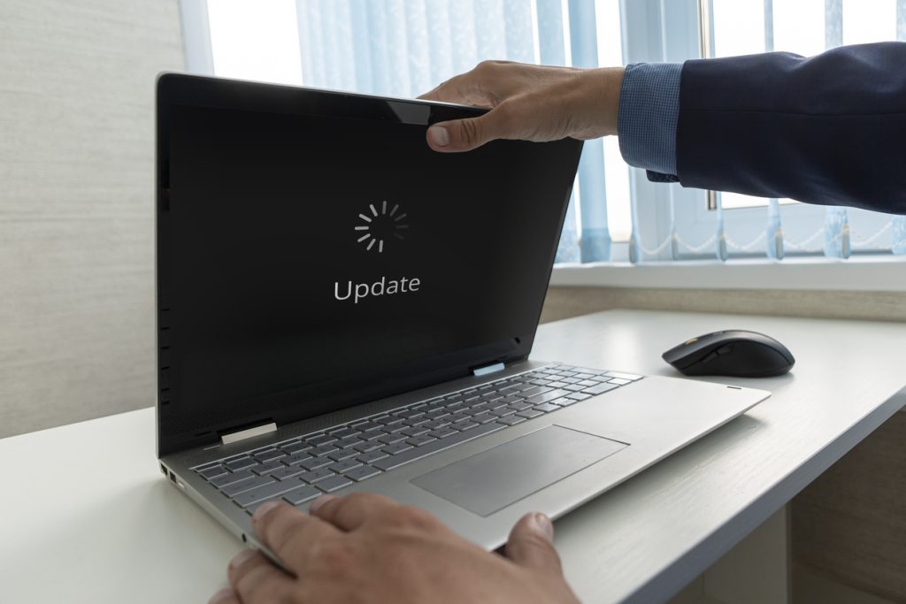 businessman opens a modern ultrabook on which the operating system is being updated. Updating Software Technology Upgrade Concept